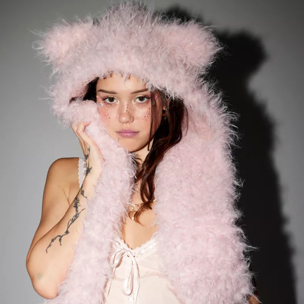 Person wearing a fluffy pink hooded garment against a gray background